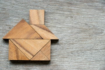 Tangram puzzle in home shape on wood background