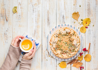 Autumn background with pumpkin pie, hot tea, yellowed leaves, book and rug. Perfect sunny autumn. A wooden light white autumn background for you. Copy Space. Place for text. Flat lay, top view