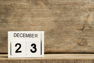 White block calendar present date 23 and month December on wood background