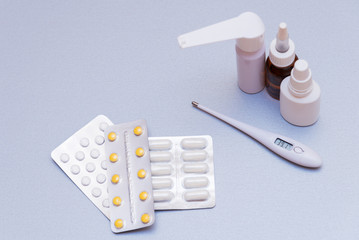 Medications and a thermometer on a light background