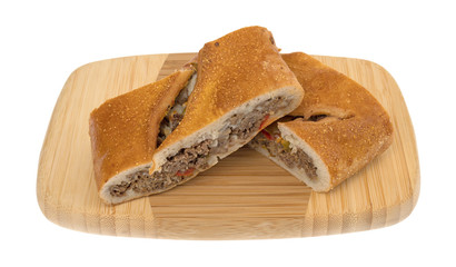 Two slices of a baked steak stromboli on a wood cutting board isolated on a white background. © Bert Folsom
