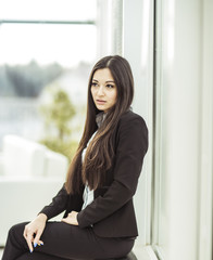 portrait of a young female assistant next to the window in the office