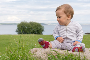 The boy is sitting on a stone with a view of the beautiful coast