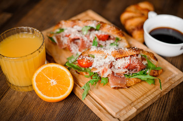 Tasty breakfast consisting of burger with ham bone, cherry tomatoes and arugula