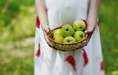 A pregnant woman monitors the health of your baby holding green fresh apples