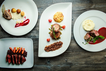 wooden table topped with white plates with different types of food in restaurant