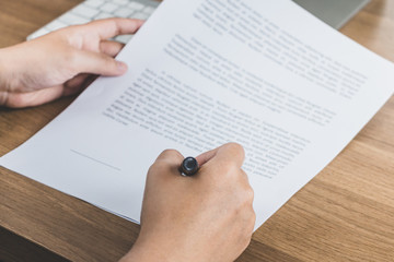 Business man signing agreement paper on wooden table, signing concept