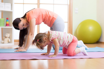 Mother and child daughter practicing yoga together at home. Sport and family concept - 180734613