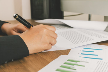 Close up business woman signing terms of agreement documents on her desk, signing concept