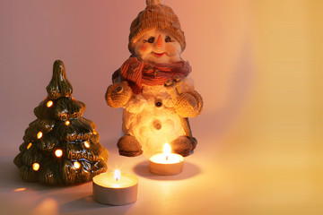 Christmas arrangement. Christmas snowman, candles and Christmas tree. Candles burn. Merry Christmas. Happy New Year. Card