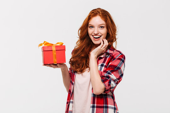 Image of Happy ginger woman in shirt holding gift box