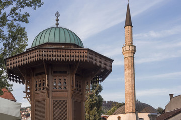 Architectural close up of the top of Sebilj fountain and mosque minaret in Sarajevo city centre