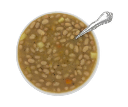 Top view of a bowl filled with bean and carrot soup with a spoon in the food isolated on a white background.