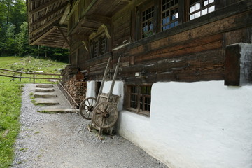 Altes schweizer Bauernhaus mit Holzvorrat und Holzkarren