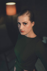 Retro woman in green dress standing in room at night.