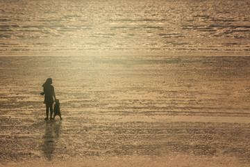 Fototapeta na wymiar Silhouettes Of Mother And Son On Beach At Sunset.