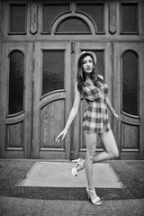 Amazing long legs with hig heels girl wear on hat posing against large wooden doors.