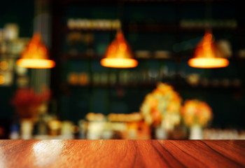 top of wood counter with blur three lamp light in pub or bar background at night
