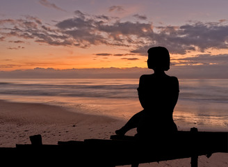 Silhouette of a woman sitting in a sunrise