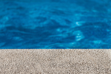 Half concrete wall and blue water background of the pool and waters in the background