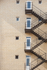 Fire Escape Stairs on the building. Construction with windows, walls of brickwork. Vertical orientation