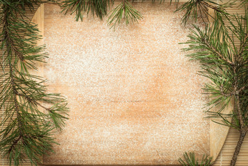 A wooden board sprinkled with flour. Frame made of fir branches. Christmas, New Year greeting card....