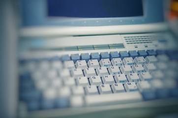 Alter Laptop aus den 90ern mit verschwommenem Hintergrund und Tastatur - obrazy, fototapety, plakaty