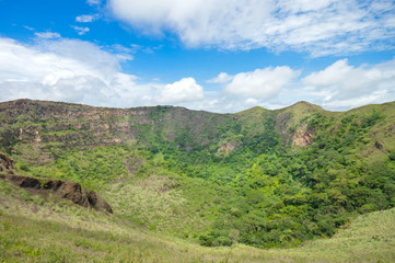 Fototapeta na wymiar Green slopes of the dormant crater of Masaya Nindiri Vocano duo near Masaya, Nicaragua. Blue sky background