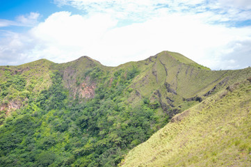 Obraz premium Green slopes of the dormant crater of Masaya Nindiri Vocano duo near Masaya, Nicaragua. Blue sky background