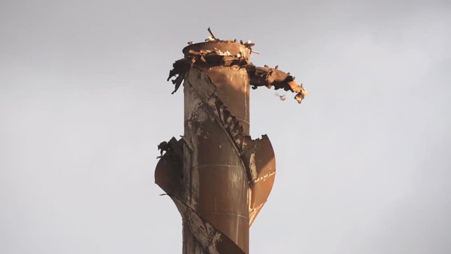 An old, rusty industrial shaft from a silo with birds roosting.