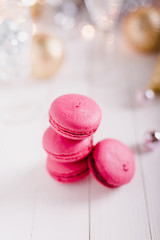 Four cute pink cheery raspberry piled macaroon cookies on a white wooden table with a holiday Christmas mood