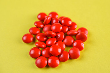 bright red pills on a yellow background.