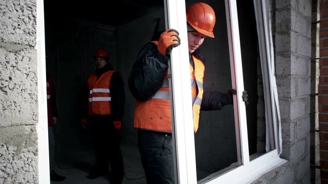 Man insert a plastic window in the opening in the building