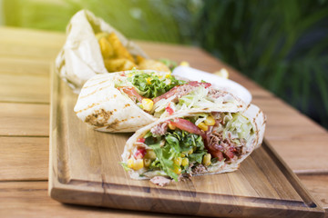Burrito with grilled chicken and vegetables. Shawarma from juicy beef, lettuce, tomatoes, cucumbers, paprika and onion in pita bread.