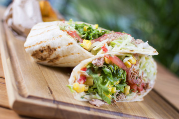 Burrito with grilled chicken and vegetables. Shawarma from juicy beef, lettuce, tomatoes, cucumbers, paprika and onion in pita bread.
