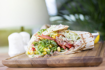 Burrito with grilled chicken and vegetables. Shawarma from juicy beef, lettuce, tomatoes, cucumbers, paprika and onion in pita bread.
