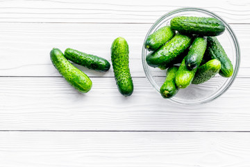 Fresh cucumbers at the bowl. Grey wooden background top view copyspace