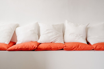 White and orange square pillows on white cozy seat sofa, flat image, blank copy space