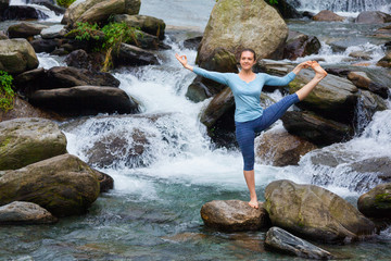 Woman doing Ashtanga Vinyasa Yoga asana outdoors at waterfall