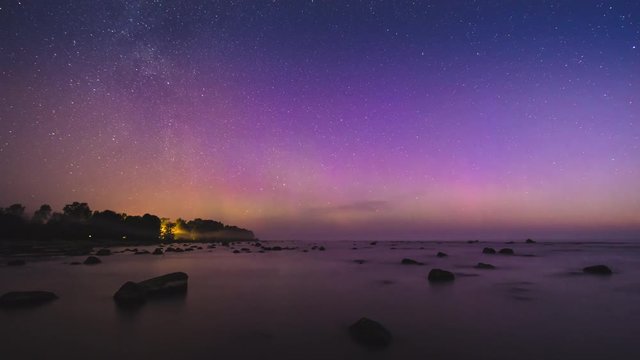 Time lapse of aurora borealis on a stony beach with big rocks in Kaltene, Latvia