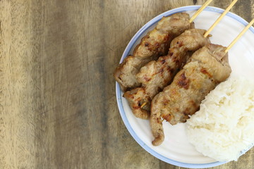 Top view of roasted pork with white sticky rice on white dish on wood table, have copy space for put text