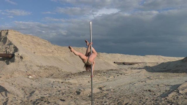Woman dances on a pylon sports dances, she is a gymnast.