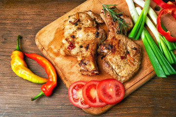 Grilled juicy steak on the bone with vegetables on a dark wooden background.