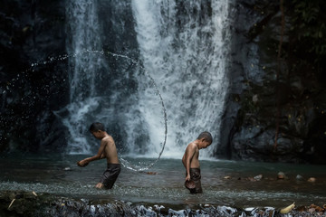 Two children playing water in the river at countryside Thailand.