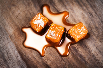 Homemade salted caramel pieces  on wooden  background. Golden Butterscotch toffee candy caramels with copyspace