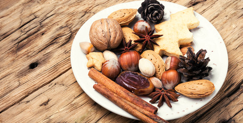 Fototapeta na wymiar Christmas plate with nuts, spices and cedar cone