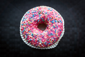 Pink donut with colorful sprinkles isolated on background