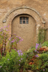 Plastered wall with arch and window in fron of defocused blossoms