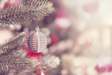 Closeup of silver bauble hanging from a decorated Christmas tree with bokeh, copy space. Xmas holiday background.