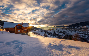 wooden chalet in village outskirts at sunrise. gorgeous landscape in winter Carpathian mountains,...